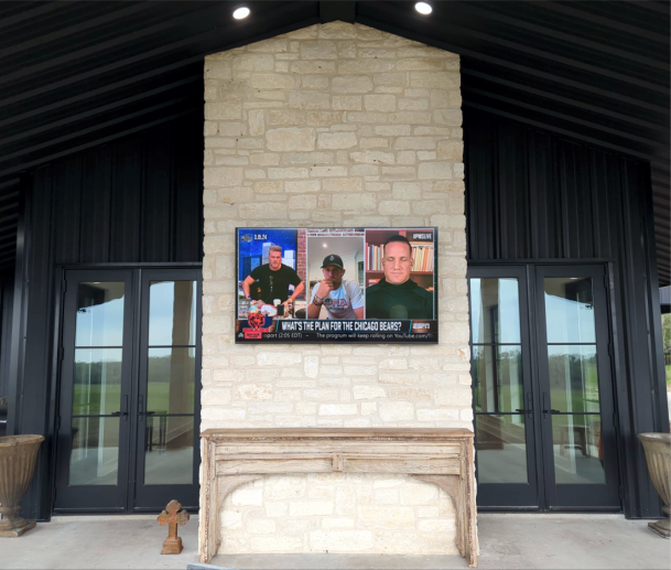 Outdoor stone fireplace with mounted TV display
